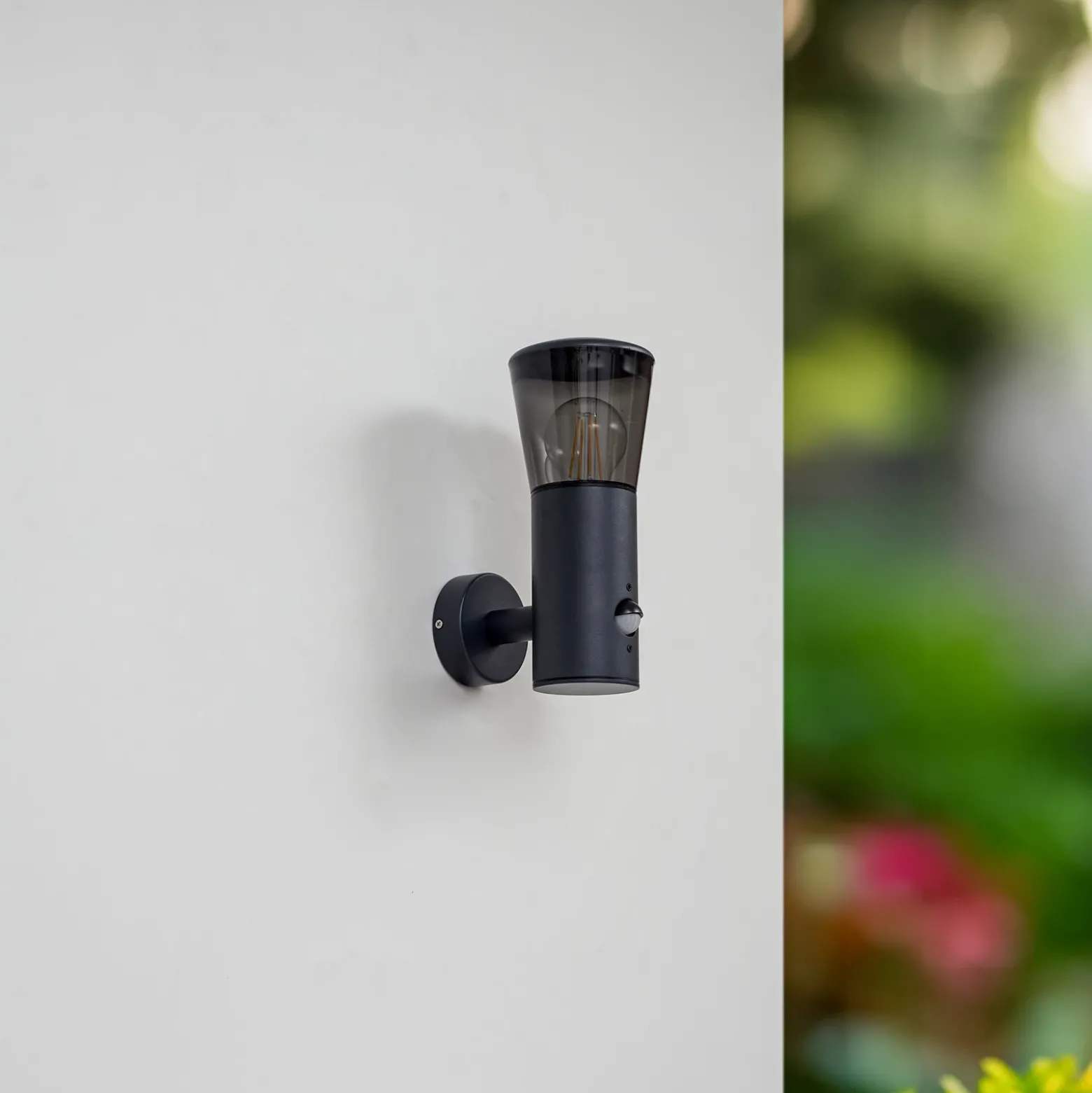Aplique de exterior Lindby Heulo, Ø 10,5 cm, gris humo, con sensor
