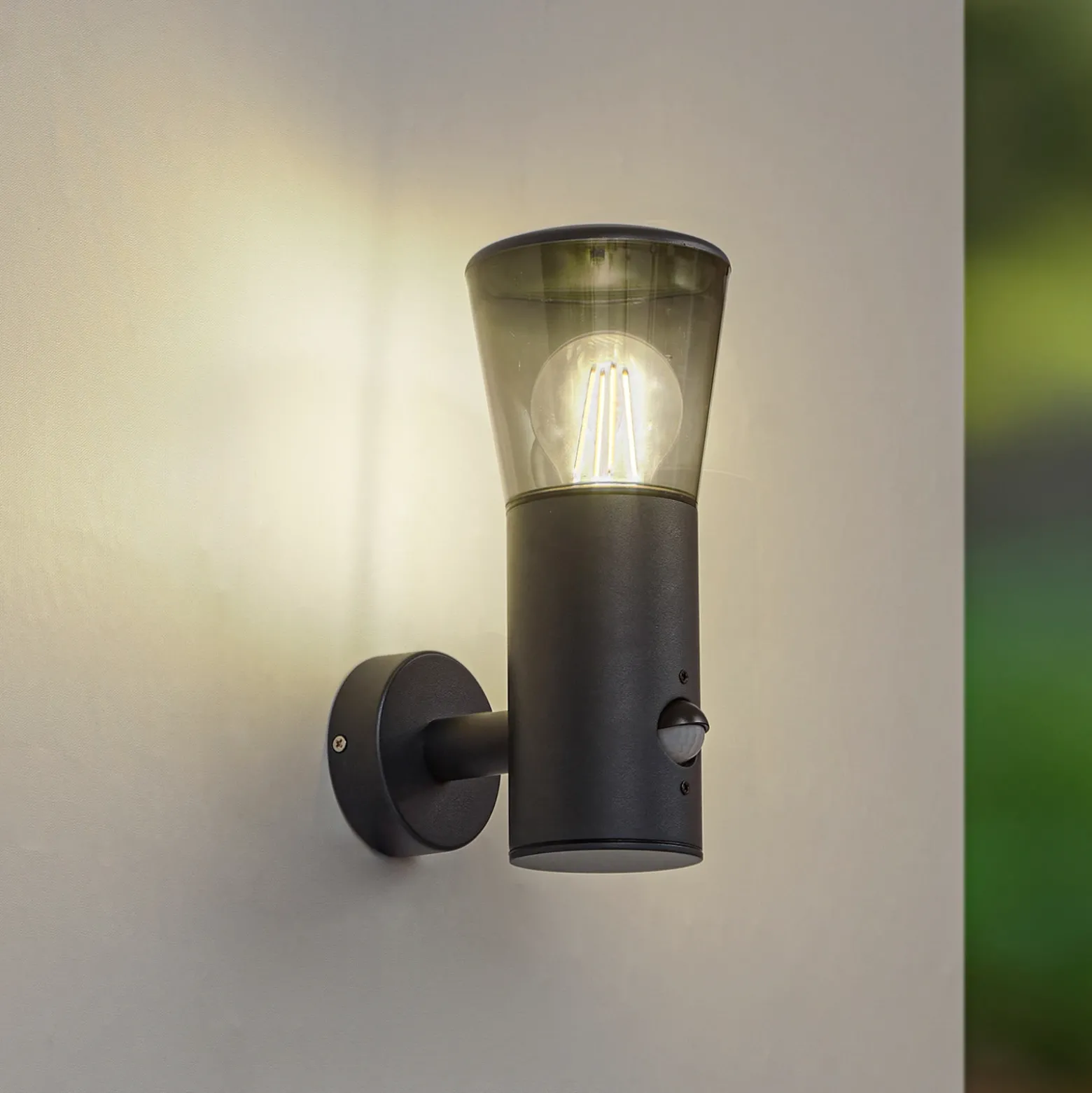 Aplique de exterior Lindby Heulo, Ø 10,5 cm, gris humo, con sensor
